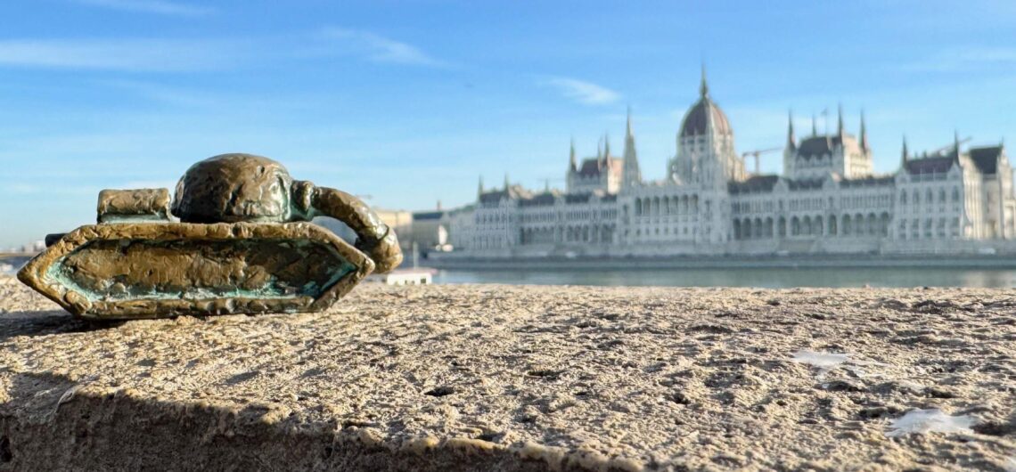 The sad tank: Kolodko mini statue near the Danube with the Hungarian Parliament building in the background, Budapest