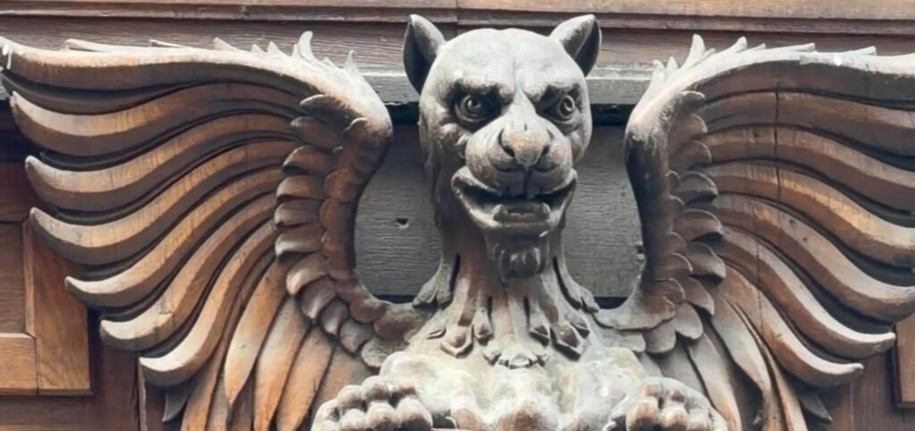 Winged mythical creature hidden among the architecture details of a historic Budapest building.