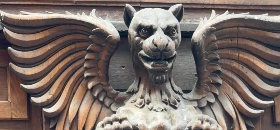 Winged mythical creature hidden among the architecture details of a historic Budapest building.