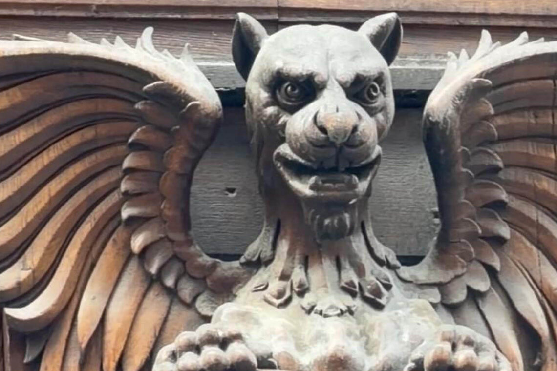 Winged mythical creature hidden among the architecture details of a historic Budapest building.