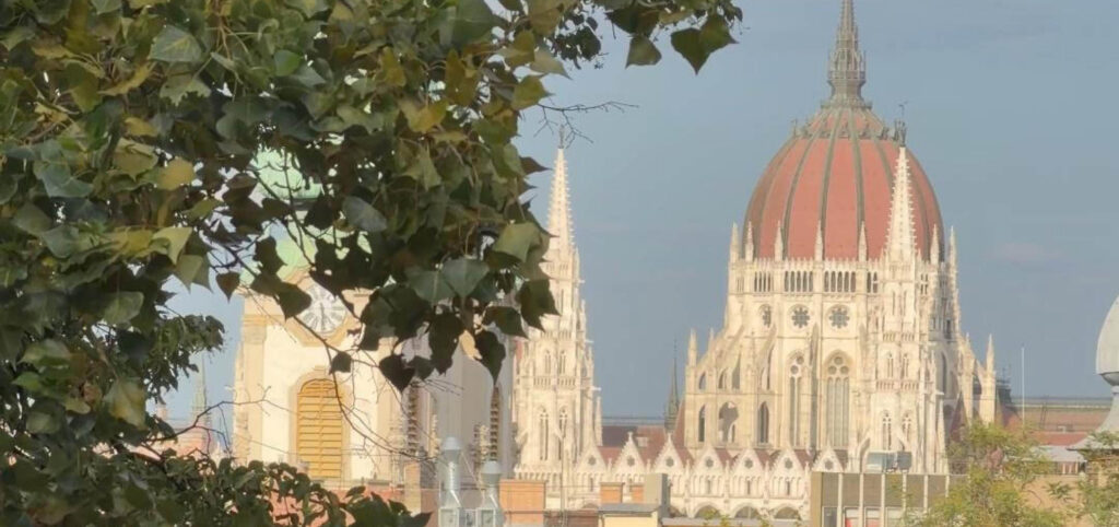 Budapest in early autumn with Parliament seen through green foliage