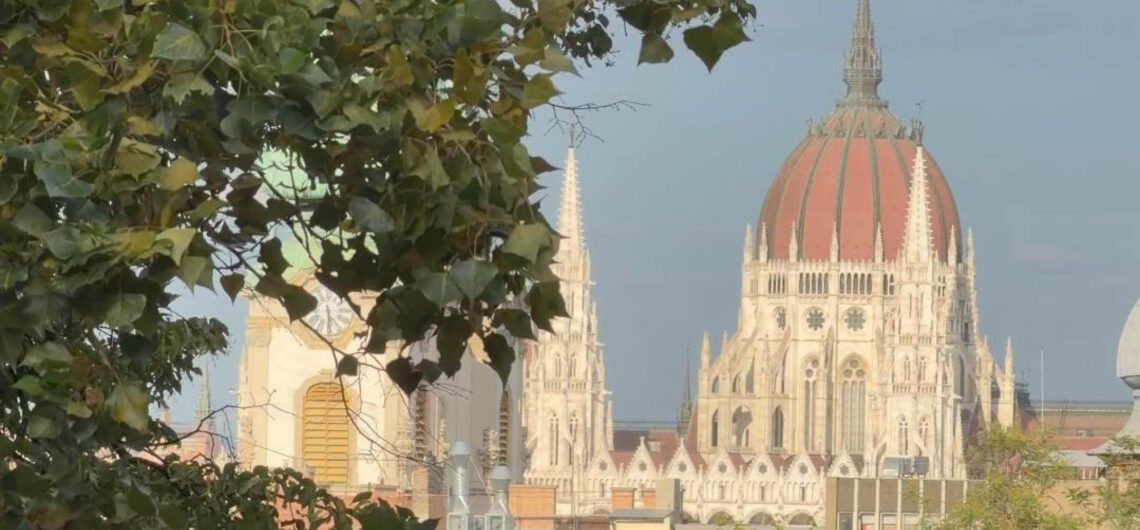 Budapest in early autumn with Parliament seen through green foliage